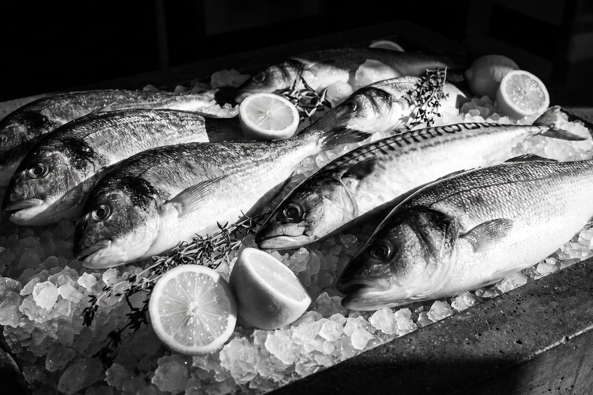 Fresh whole fish on ice with lemon halves
