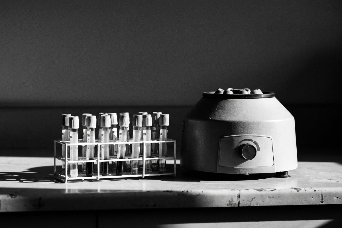 Blood collection tubes in a rack beside a laboratory centrifuge
